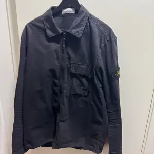 Overshirt från Stone Island i dyed wash svart färg med en ficka på framsidan. Storlek XL men kan även passa L. Säljes då den inte används längre. 