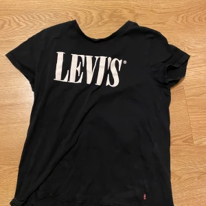 Svart t-shirt från Levi's, - Säljer en svart t-shirt från Levi's i storlek M. Den har en klassisk design med korta ärmar och Levi's-loggan tryckt i vitt på framsidan. Perfekt för en avslappnad stil eller vardagsbruk. Passar bra till jeans eller shorts! Pris kan diskuteras.