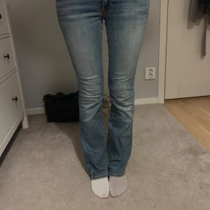 Blå bootcut jeans - Säljer ett par snygga blå bootcut jeans i bra skick. De är lågmidjade och har en snygg brodyr på fickorna. Perfekta för både vardag och fest! Passar till allt från sneakers till klackar.