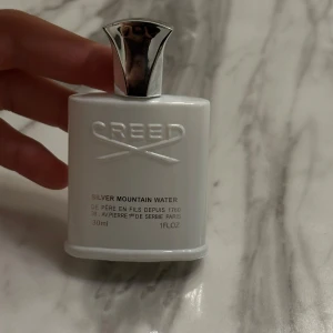 Silver Mountain Water från Creed - Säljer en elegant parfymflaska från Creed, Silver Mountain Water. Flaskan är vit med en stilren design och har en silverfärgad kork. Innehåller 30 ml av en fräsch och uppfriskande doft som påminner om bergsluft och rena vattenkällor. Perfekt för både vardag och speciella tillfällen. Helt ny köpt 2 dagar sen 