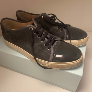 Lanvin skor - Säljer nu ett par lanvin skor i färgen grå, skorna är rätt så använda och hade hål i båda sulorna vilket gjorde att det läckte in vatten, lämnade in dom för lagning och då satte dom dit en ny gummi sula samt ny inner sula. Säljs billigt pga av skick.