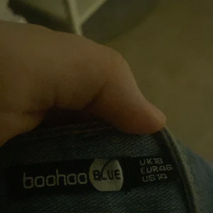 Blå jeans med slitningar från Boohoo - Säljer ett par snygga blå jeans från Boohoo i storlek EUR 46. De har coola slitningar på framsidan som ger en trendig look. Perfekta för en avslappnad stil och kan matchas med nästan vad som helst. Passar bra till både vardag och fest!