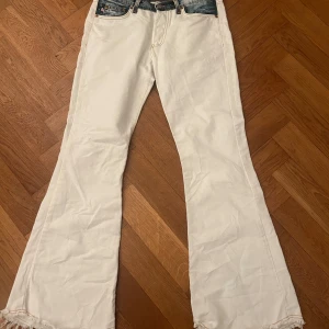 Vita bootcut jeans med fransar - Säljer ett par vita bootcut jeans från C-girl. De har en cool fransdetalj vid bensluten och blå denimdetaljer vid midjan och fickorna. Passar s-m