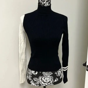 Ribbad tröja - Zaraknit  - Säljer en unik svart och vit ribbad tröja med en cool asymmetrisk design. Ena ärmen är vit och ribbad medan den andra är svart med vita ränder vid ärmslutet. Perfekt för att sticka ut i mängden! 🖤🤍