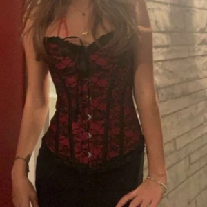 Svart och röd korsett - Snygg korsett i svart och rött med spetsdetaljer och snörning framtill. Perfekt för halloween (lånad bild)