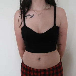 Svart croppad topp - Säljer en snygg svart croppad topp med smala axelband. Perfekt för sommaren eller en utekväll. Toppen är i ett mjukt material och sitter tight för en smickrande passform. Passar bra till både jeans och kjol!