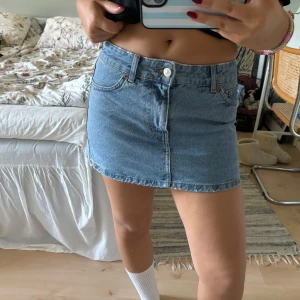 Mini jeanskjol💙 - Säljer en superfin blå jeanskjol i kort modell. Kjolen har en klassisk femficksdesign och stängs med knapp och dragkedja framtill. Den är i bra skick och passar perfekt till en t-shirt eller en söt topp. 🦋