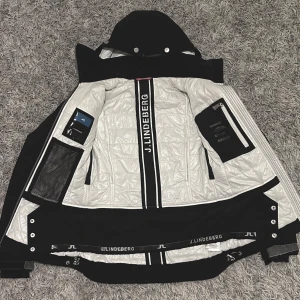 JLindeberg Aspen Jacket - Jättefin vinterjacka från JLindeberg. Använt som skidjacka men funkar även som vinterjacka. Använd 2 gånger.  Köpt på JLindeberg för 5500kr.  Storlek XS. Svart yttersida och vit innersida med svarta innerfickor med blixtlås. Vattentålig. Kom m. Bud!
