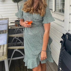 Grön klänning - Grön omlottklänning med vita prickar. Bandet i midjan gör att den går att justera i storlek 💚Tror den är storlek L men passar mig i S