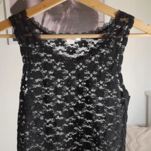 Svart spetslinne gina tricot - Elegant svart spetsllinne med ett vackert mönster. Den har en klassisk design som passar till många tillfällen.