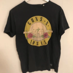 Svart Guns N' Roses t-shirt från Shine Original - Guns N’ Roses från Shine Original. T-shirten har en klassisk rund hals och korta ärmar. Tröjan är lite äldre och har några få små hål men övrigt i bra skick🌸