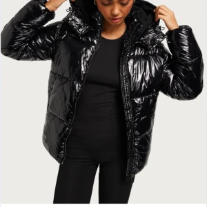 Svart glansig pufferjacka från Nelly - Jätte snygg svart pufferjacka från nelly!!! Säljer då den inte kommer till användning. Kommer inte sänka mig mer än till 300kr😊