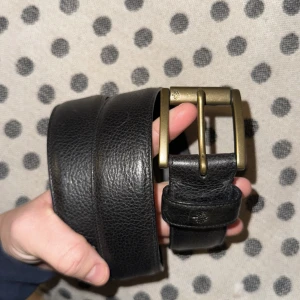 Svart skärp från Mulberry - Snyggt svart skärp i skinn från Mulberry med en stilren metallspänne i mässing. Perfekt för att ge en klassisk touch till din outfit🇮🇹🖤🤗