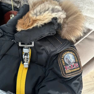 Svart dunjacka med pälsdetaljer - Säljer en svart dunjacka från Parajumpers med pälsdetaljer på huvan. Jackan är väl använd men fortfarande jättefint skick! Pälsen är stor och fluffig.