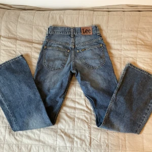 Lee jeans lågmidjade  bootcut W26 L31 - Jätte fina Lee jeans i lågmidjade bootcut stil. Jeansen är i bra skick, men lite slitna neders på benen, se bild. Midjemått är 32 cm och innerben längd 76 cm.  Tveka inte att höra av dig för frågor eller flera bilder. 