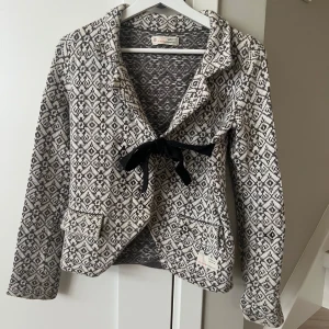 Kofta från Odd Molly - Säljer en snygg mönstrad kofta från Odd Molly i grått och vitt. Koftan har långa ärmar och en fin knytning framtill. Använd 1 gång.
