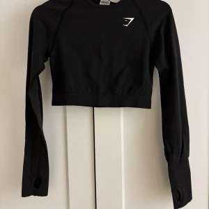 Gymshark cropped long sleeve topp - Vital seamless 2.0 long sleeve crop top. Säljer en svart croppad tröja från Gymshark med långa ärmar och tumhål. Endast använd fåtal gånger. Nypris 400kr