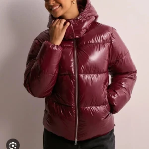  Vinröd pufferjacka Nelly -  slutsålda Nelly jackan! Snygg vinröd pufferjacka med dragkedja och hög krage. Perfekt för kyliga dagar med sin vadderade design som håller dig varm och bekväm. Jackan har långa ärmar och en glansig finish som ger en modern touch. Använd 2-3 gånger inga slitage❤️❤️