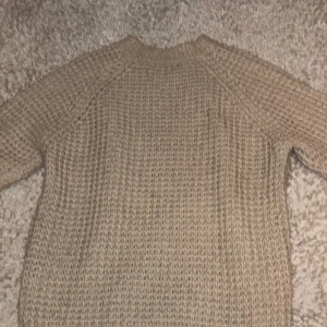 Beige stickad tröja - Säljer en mysig beige stickad tröja med långärmad design. Perfekt för kyligare dagar och ger en avslappnad look. Tröjan har en enkel och stilren stil som passar till det mesta. Perfekt för höst och vinter!