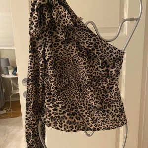 Leopardmönstrad oneshoulder topp!  - Snygg leopardmönstrad oneshoulder topp med lång ärm och knytband vid axeln. Perfekt för att ge en vild touch till din outfit. Endast använd vid ett fåtal tillfällen så är i perfekt skick! 