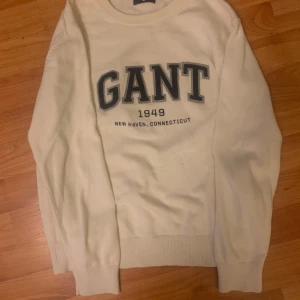 Vit tröja från GANT - Säljer en vit tröja från GANT med tryck framtill. Tröjan har långa ärmar och ribbade muddar vid ärmslut och nederkant. Storlek 158-164.