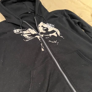Svart hoodie med tryck - Säljer denna hoodien fick den av en kompis vet inte vad det är för märke men den e skön iallafall