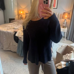 Svart stickad tröja med knappar - Säljer en blå stickad tröja med rund hals och dekorativa knappar på axeln. Den har en liten slits på båda sidorna, från Filippa k