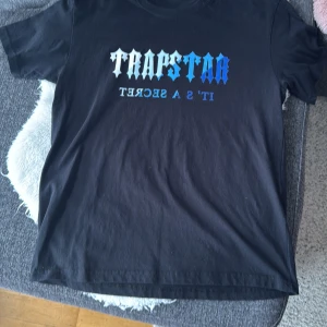 2 st svarta t-shirt från Trapstar - Säljer 2 st  svarta t-shirt från Trapstar med texten 'It's a Secret' . T-shirt har en normal passform och är kortärmad, perfekt för en avslappnad stil. Storlek M. Bägge för 150kr