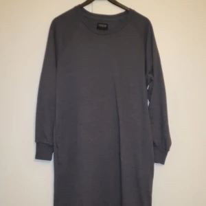 Mörkgrå klänning - Säljer en stilren mörkgrå klänning. . Klänningen har långa ärmar och en avslappnad passform, perfekt för en bekväm och trendig look. Tillverkad i mjukt material som känns skönt mot huden. Passar bra till både vardag och avslappnade tillfällen.