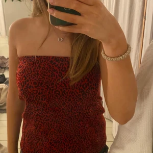 Röd leopardmönstrad tubtopp - Snygg röd tubtopp med leopardmönster. 🐆❤️Perfekt för en trendig look. Toppen är axelbandslös och har en tight passform som framhäver figuren. 