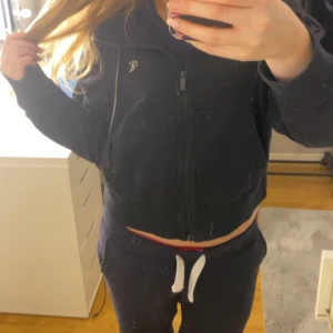 Svart hoodie från Calvin Klein - Säljer en svart hoodie från Calvin Klein med dragkedja och huva. Den har en liten CK-logga på bröstet och är tillverkad i ett mjukt material. Perfekt för en avslappnad stil.