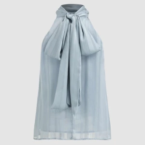 Ljusblå ärmlös topp med rosett bak - Elegant ljusblå topp med silvermönster. Ser precis ut som på bilderna! Ny utan prislapp, säljs för att jag inte hann lämna tillbaka den.💙✨