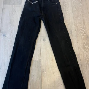 Svarta jeansbyxor från FB Sister - Coola svarta jeansbyxor från FB Sister med texten 'Los Angeles' tryckt på baksidan. Byxorna har en slim passform och är perfekta för en trendig look. De har en klassisk femficksdesign och är tillverkade i ett bekvämt material.