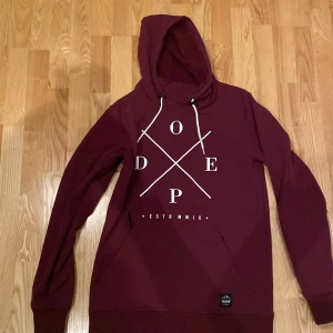 Vinröd hoodiejacka från Dope - Säljer en snygg vinröd Yeti softshelljacka från Dope. Perfekt för en avslappnad stil i slalombacken. Den hat tyvärr slitage på trycket och en fläck vid arm fickan, se bilder). Ni kan läsa om jackan Yeti för att få fler detaljer kring funktion. 