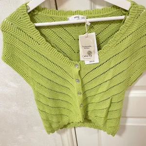 Grön stickad kofta från mango - Säljer en snygg grön stickad kofta från mango i hållbar bomull. Koftan har en v-ringning och knappar framtill. Perfekt för att lägga till en färgklick i garderoben!