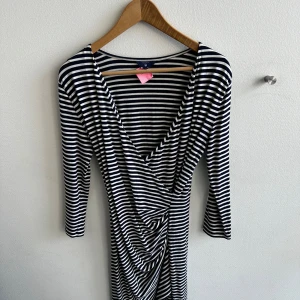 Randig klänning från GANT - Säljer en snygg randig klänning från GANT i storlek S. Klänningen har ett omlottmönster framtill och trekvartsärmar. Perfekt för både vardag och fest! 🖤🤍