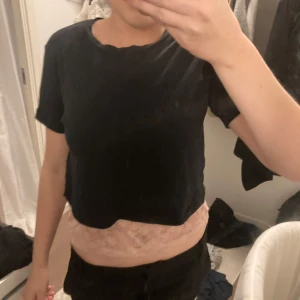 Svart croppad t-shirt - Säljer en enkel och stilren svart croppad t-shirt. Perfekt för sommardagar eller som en del av en lager-på-lager-look. T-shirten har korta ärmar och en avslappnad passform. Passar till både jeans och kjol!
