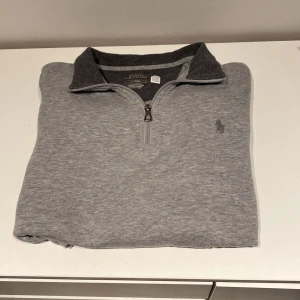 Grå half zip tröja Polo Ralph Lauren - Säljer en stilren grå tröja från Polo Ralph Lauren i storlek M men passar S. Tröjan har Inga tydliga defekter och den klassiska loggan broderad på bröstet. Perfekt för både vardag och lite finare tillfällen. Superbekväm och lätt att matcha med andra plagg!                                                           Nypris 2100kr mitt pris 850 pris kan diskuteras.  