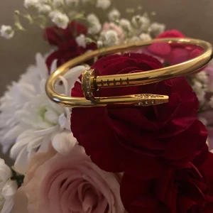 Rostfritt stål armband med nageldesign - Säljer ett unikt guldarmband med en cool nageldesign. Armbandet har en elegant och modern stil med små glittrande stenar som ger det en extra touch av lyx. Perfekt för både vardag och fest! ✨