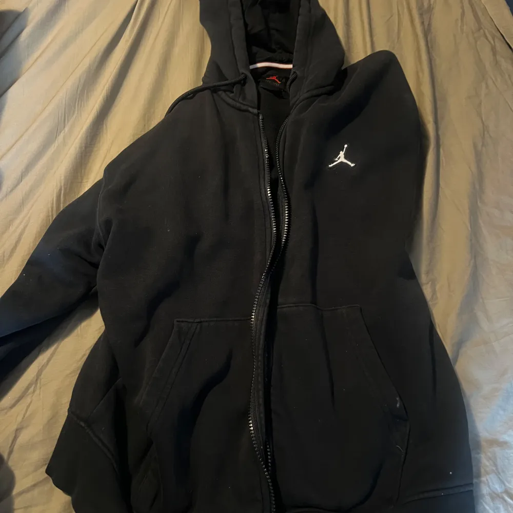 Säljer en svart hoodie från Jordan i bra skick. Den har en dragkedja framtill och en klassisk logga på bröstet. Perfekt för höst och vår, med en skön passform och fickor för extra bekvämlighet. Passar både till vardags och träning.. Tröjor & Koftor.