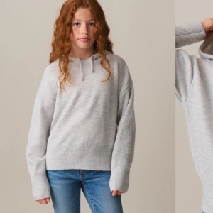 Ljusgrå stickad hoodie - Säljer en supermjuk ljusgrå stickad hoodie i storlek 146/152. Perfekt för kyliga dagar med sin mysiga huva och ribbade kanter. Helt ny med tag kvar! Passar perfekt till jeans eller leggings för en avslappnad look.
