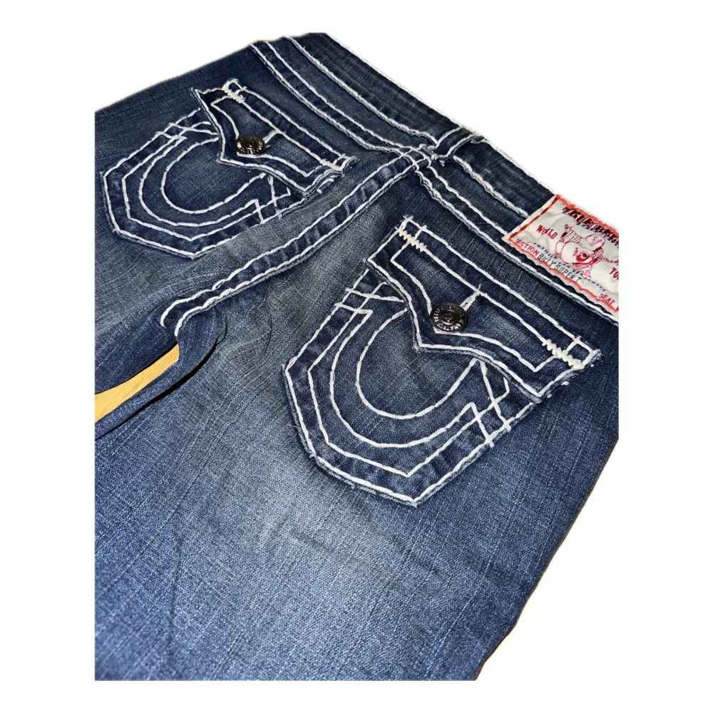 Helt nya True Religion-jeans, fortfarande med taggen på. Låg midja och utsvängd/bootcut. Midja: 38 cm. Yttersöm: 107 cm. Innersöm: 82 cm. Benöppning: 21,5 cm. Har ej foto på eftersom de ej passar mig. Ställ gärna frågor. Priset kan diskuteras.. Jeans & Byxor.