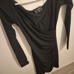 Svart klänning från AX Paris - Snygg svart klänning från AX Paris i ett stretchigt material. Den har en åtsittande passform med långa ärmar och en stilren design. Perfekt för en utekväll eller fest! 🖤