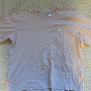 Ljus rosa t-shirt från H&M - Säljer en ljus rosa t-shirt från H&M i storlek S. Den har en enkel design med texten 'LOVE' tryckt på bröstet. Perfekt för en avslappnad stil. T-shirten är i bra skick och gjord av mjukt bomullsmaterial.