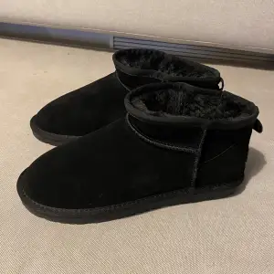 Säljer ett par svarta uggs-liknande boots, helt oanvända! De är fodrade med mjukt material. Supersköna och perfekta för kalla dagar och har en robust sula för bra grepp. Stl 42 (fast det står stl 43 på dem). 