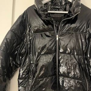 Svart glansig pufferjacka - Säljer en supercool svart glansig pufferjacka från Gina Tricot. Perfekt för att hålla sig varm och stilren under vintern. Jackan är i mycket bra skick och inga defekter!