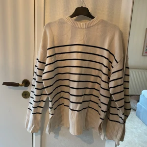 Randig tröja från Zara - Säljer en superfin randig tröja från Zara i storlek M. Den är vit/beige med mörkblå ränder och har en skön, loose passform. Perfekt för både höst och vinter! Tröjan är i mycket bra skick och gjord av mjukt material som känns härligt mot huden. Passar perfekt till jeans eller kjol för en avslappnad look.