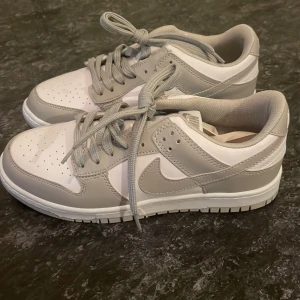 Grå vita Nike sneakers - Säljer ett par snygga Nike sneakers i grått vitt. Helt oanvända och nya! I storlek 39. Inte äkta Nike!!!