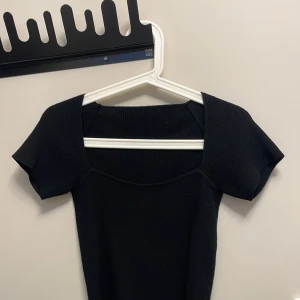 Svart ribbad topp från Dazy - Säljer en snygg svart ribbad topp från Dazy/ shein i storlek S. Toppen har en tight passform och korta ärmar, perfekt för både vardag och fest. Den är i mycket bra skick och passar till alla tillfällen. Säljer för den kommer aldrig till användning.