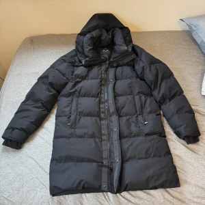 Svart dunjacka från Everest - Säljer en svart dunjacka från Everest i mycket bra skick och i storlek s men oversize. Den har två stora fickor på framsidan med dragkedjor och den är perfekt för kalla vinterdagar med sin tjocka vaddering och långa ärmar. Jackan har en praktisk dragkedja och en hög krage för extra värme. Perfekt för både vardag och utomhusaktiviteter! Väldigt varm och skön jacka, knappt använd med inga tecken på användning. Kostar runt 3000 i vanliga fall. Pris kan diskuteras